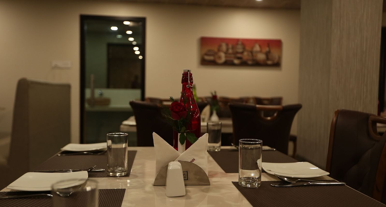 A well-lit restaurant area with dark wood furniture and table settings  - TGI SPS Grand, Coimbatore