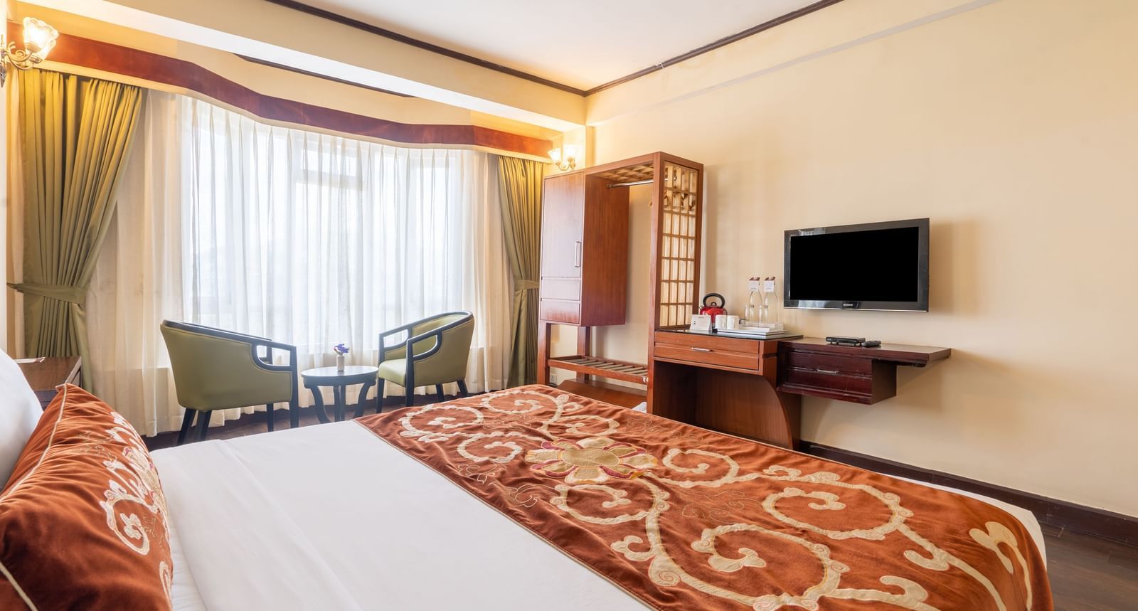 king size bed and chairs in the background near balcony of premium room at Summit Lillium Hotel & Spa, Kalimpong