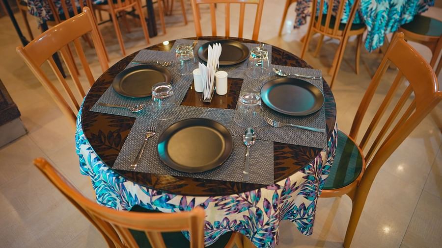 A round table surrounded by chairs, with plates arranged on top