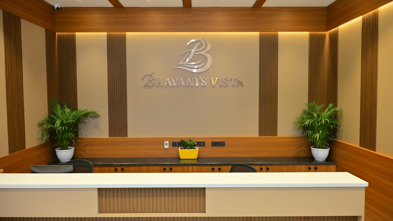 Reception desk of Bhavanis Vista By Icon featuring a counter, signage, and potted plants.