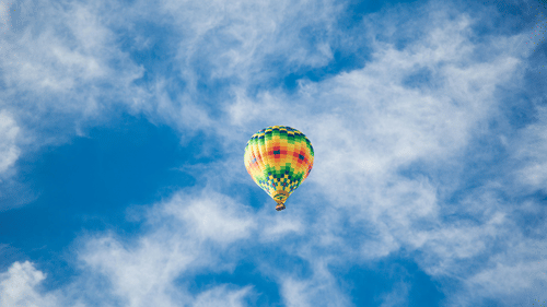 A bright coloured hot air balloon flying in the sky.