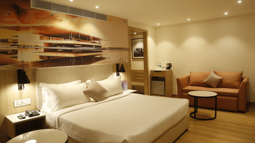 A bedroom with warm tones, a king size bed, and cosy decor - Tulip Inn, Zirakpur