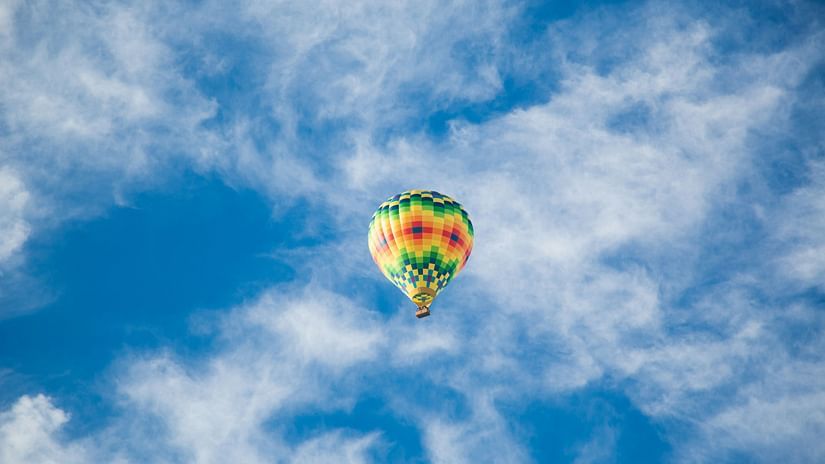 a vibrantly coloured hot air balloon flying in the blue sky
