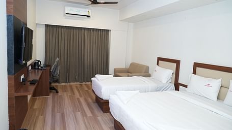 a room featuring a double bed along with a single bed along with huge windows with curtains drawn over it - Hotel Grand Sigma