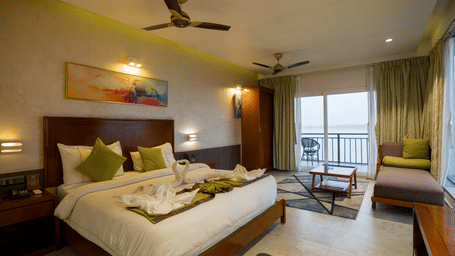 Superior Room with double bed, green accents, and balcony door at Hotel Sonar Bangla, Taki.