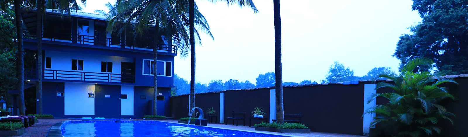 NA-Image of a swimming pool with a building behind and trees beside at Parampara Resort & Spa.