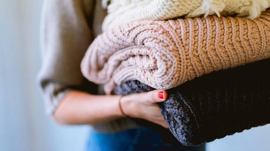 A woman holding neatly folded clothes, symbolizing fresh laundry and cleanliness