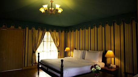 A white bed surrounded by walls with patterns of vertical lines