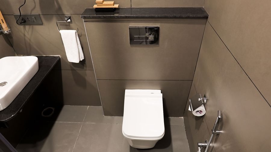A bathroom at Hotel Kyzen HiTech City – Your Zenly Stay with sleek sink, hand shower, rolling tissue papers and wall-mounted fixtures.