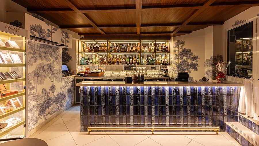 A sophisticated bar with a wooden ceiling, illuminated counter, and an extensive collection of beverages