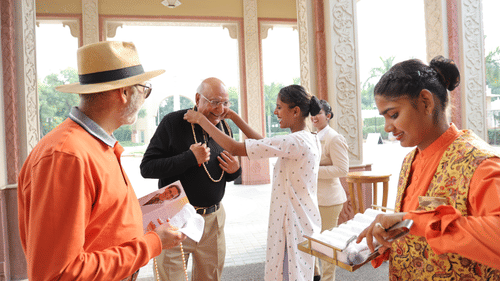 Hotel staff welcoming visitors with refreshments in a beautifully designed outdoor space.