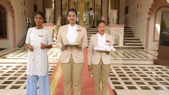 Hotel staff standing gracefully in traditional attire, greeting guests at the entrance.