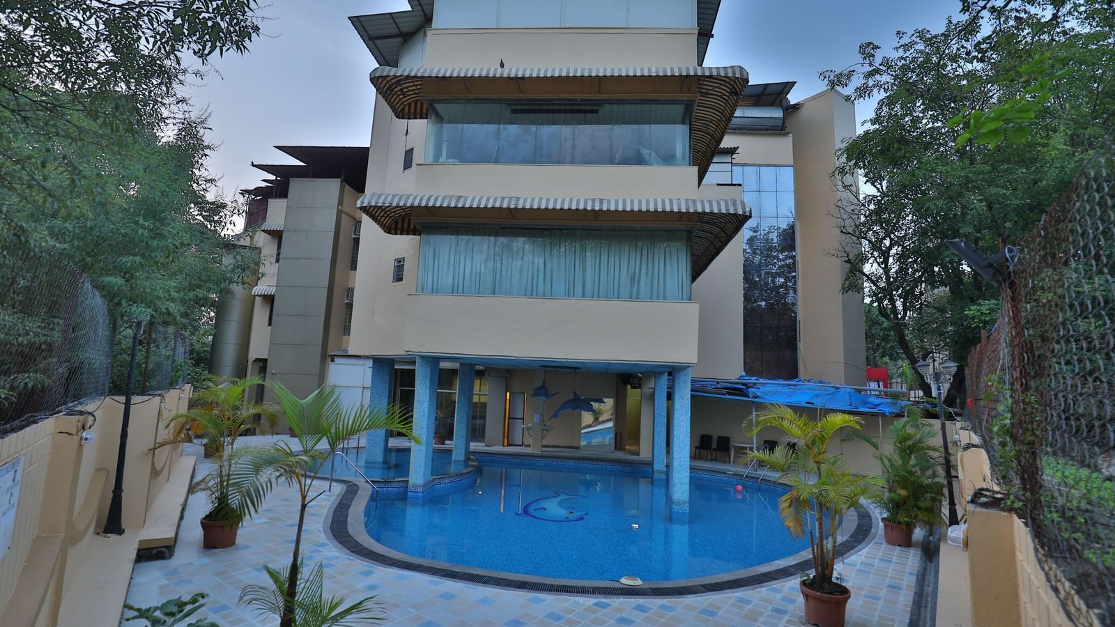 The exterior of a multi-story hotel building with a visible swimming pool in the foreground - Retreat Heritage, Lonavala