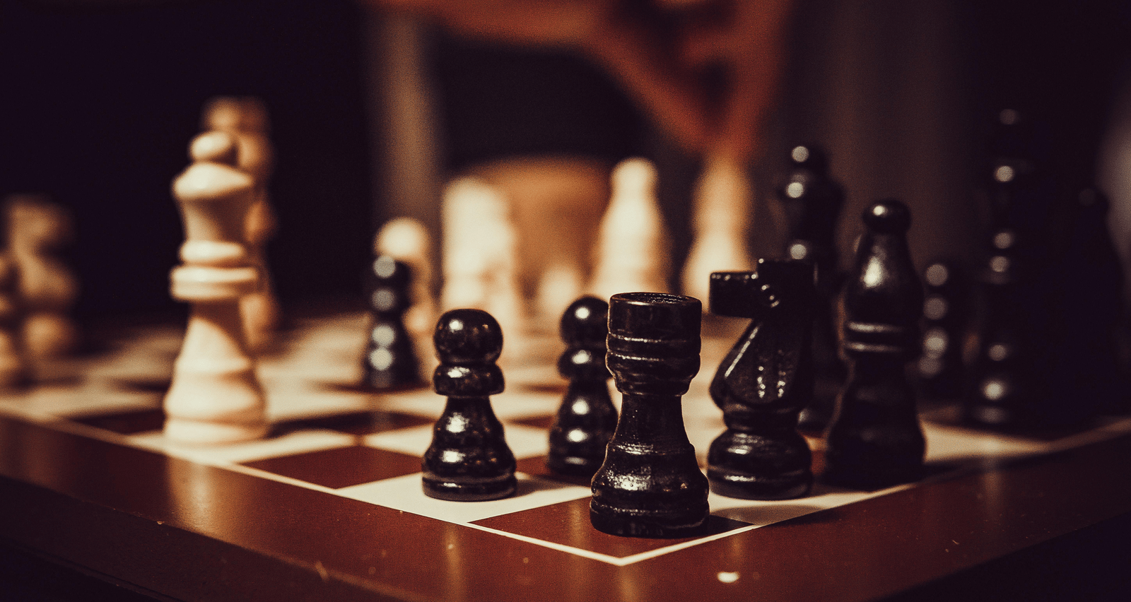 A close-up of a chessboard with the black pieces clearly in focus on the right side.