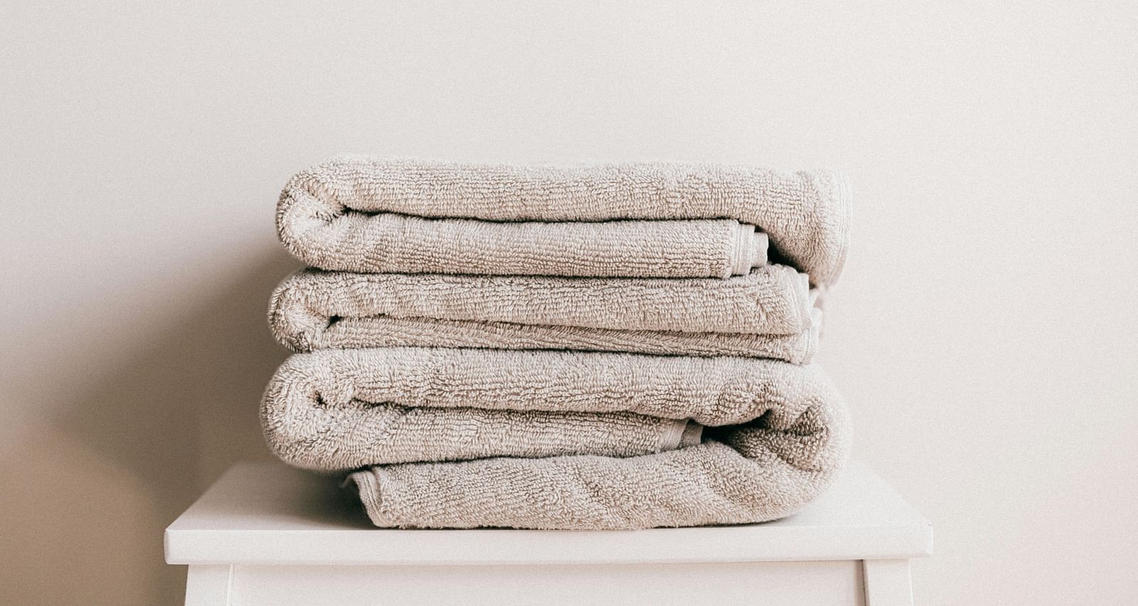 a few white coloured towels neatly folded and kept on a stool