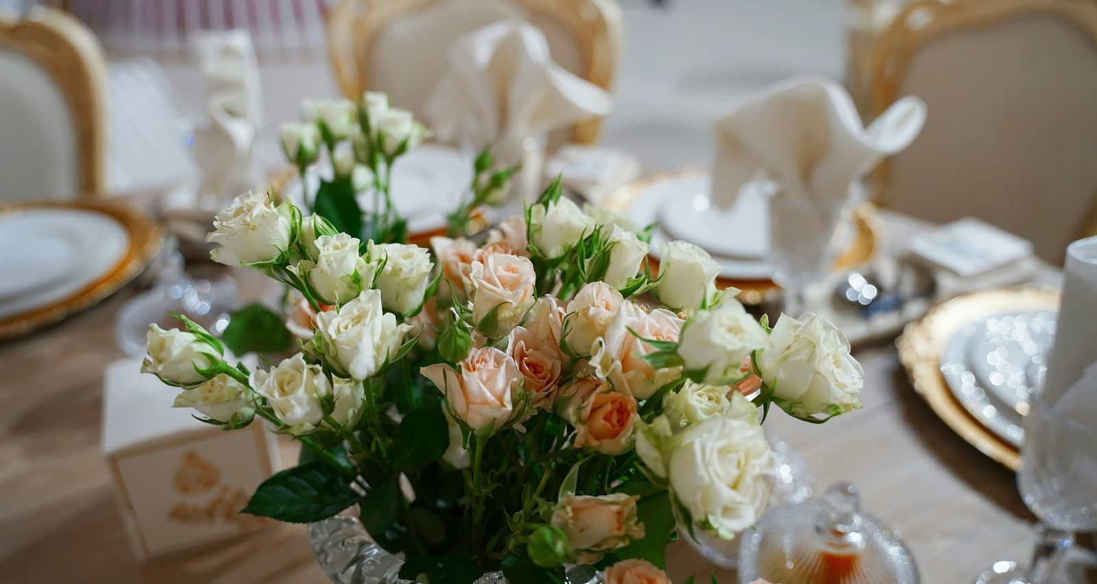 a close up image of a beautiful flower vase with a lot of white and pink roses on a dining table