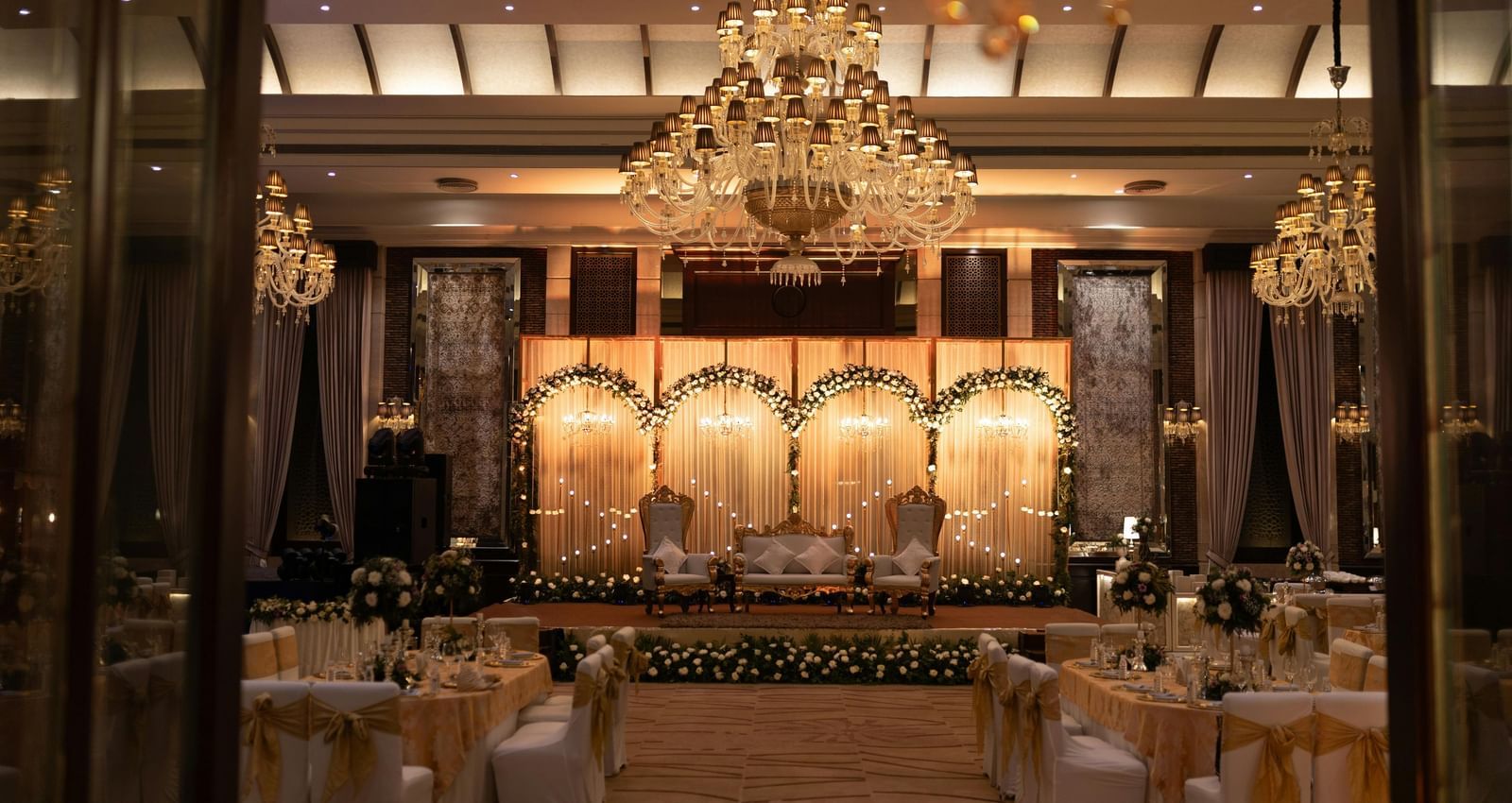 A luxurious reception area, richly decorated with warm lighting, chandeliers, and classical styling