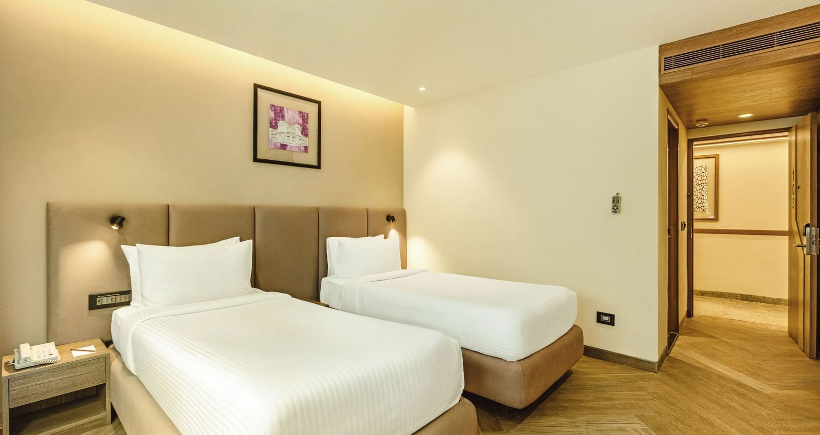 A twin-bedded room with a television and a desk, seen from an angle, at Mango Hill Central, Chennai.