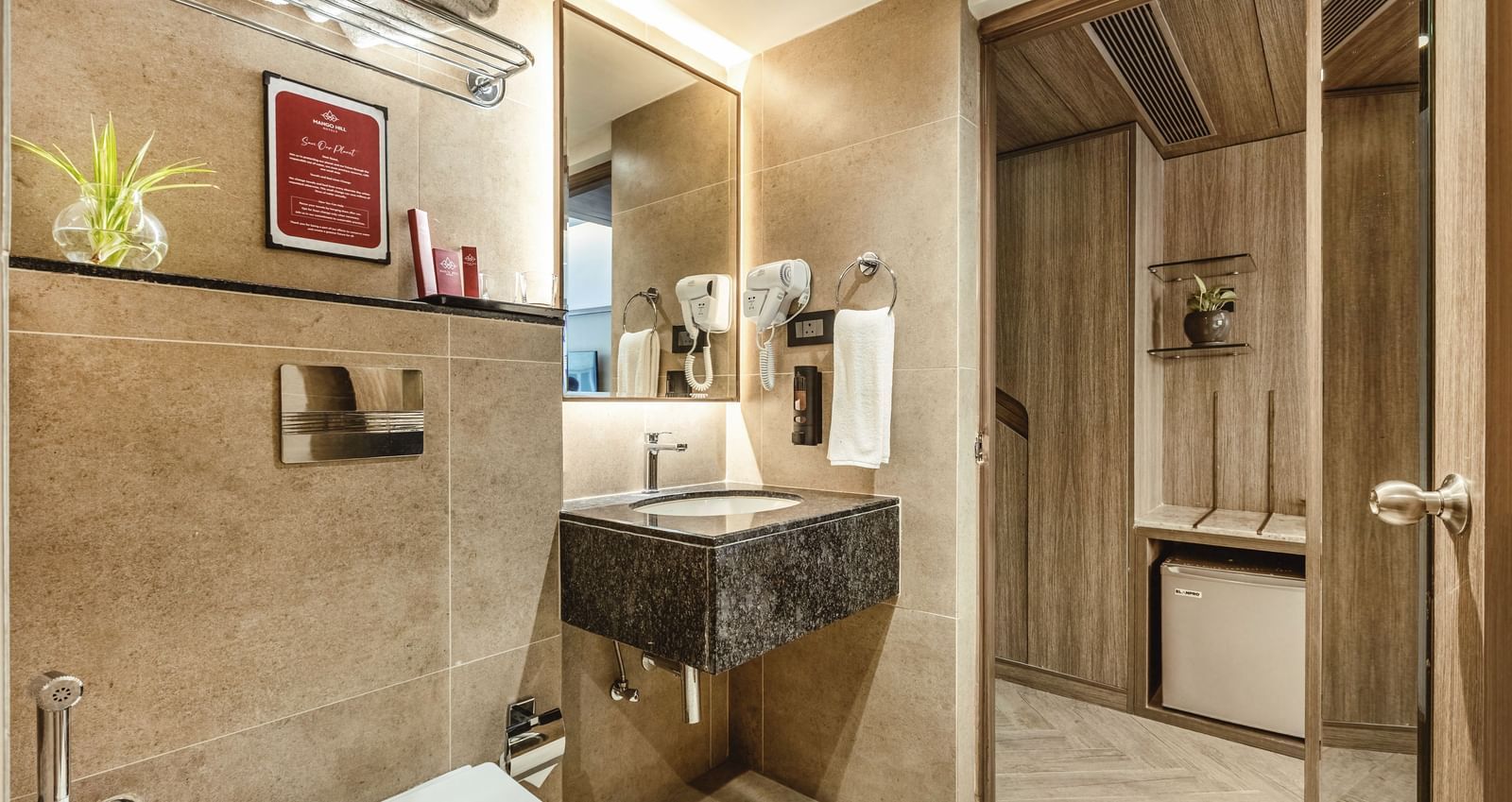 A bathroom at Mango Hill Central, Chennai, with a black-topped sink, mirror, and toilet visible.