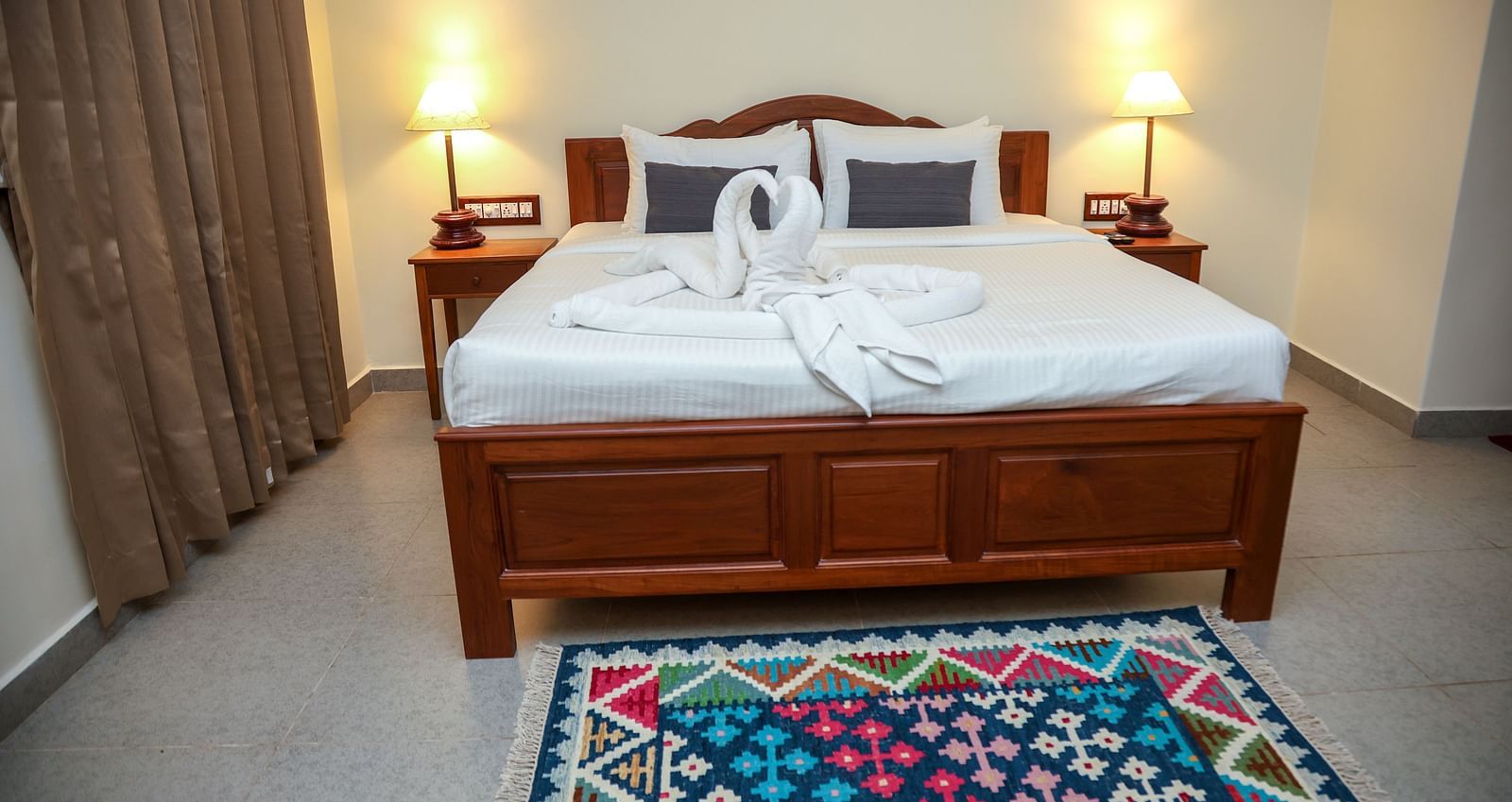  A room with double-sixed bed, lamp on either side, and a window covered by a curtain | Mango HIll La Serene, Ponicherry