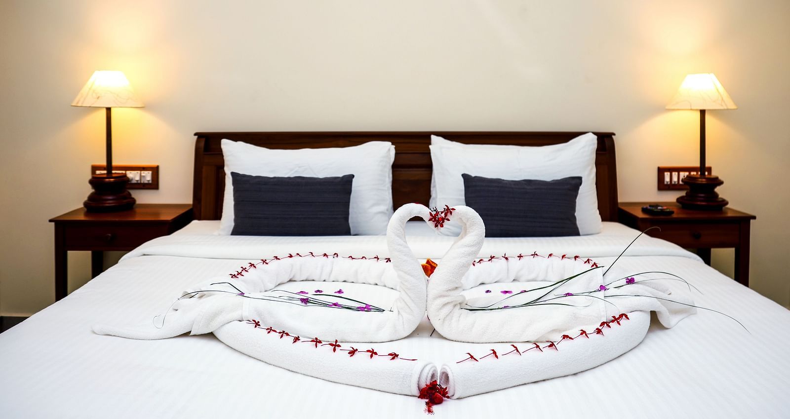 A large bed decorated with towel swans and flower petals | Mango Hill La Serene, Pondicherry