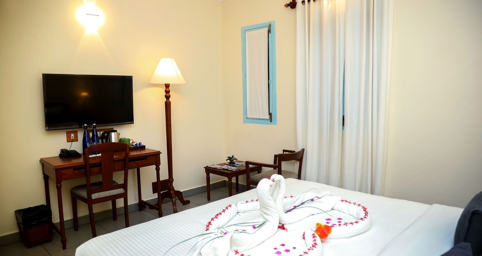 A bedroom which has a bed decorated already and a flatscreen TV | Mango Hill La Serene, Pondicherry
