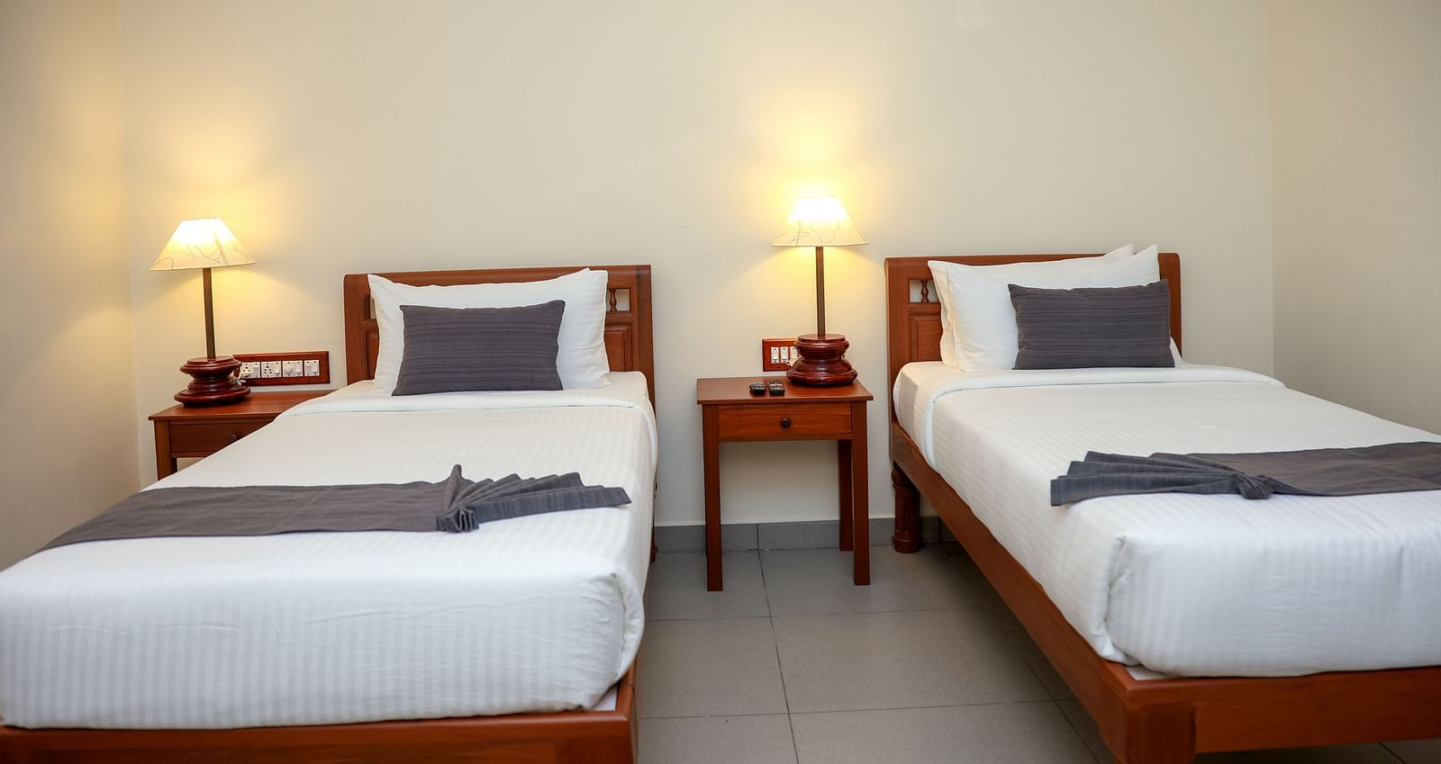 Twin beds with bedside table for each in a room  | Mango Hill La Serene, Pondicherry