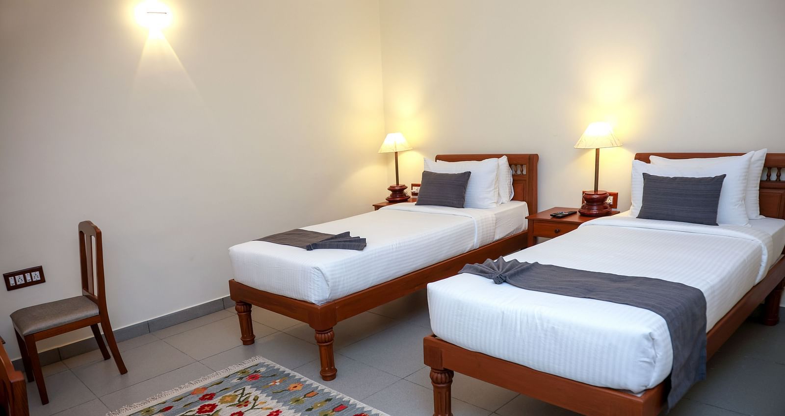 Twin beds and a chair in a room  |Mango Hill La Serene, Pondicherry