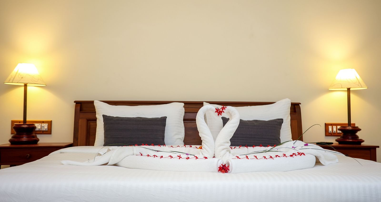 A large bed decorated with towel swans and flower petals | Mango Hill La Serene, Pondicherry
