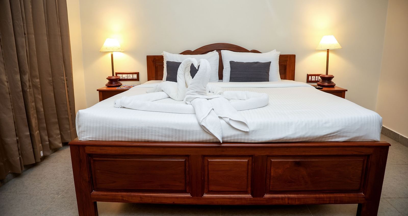 A bed that has two swans made out of towels at Mango Hill La Serene, Pondicherry