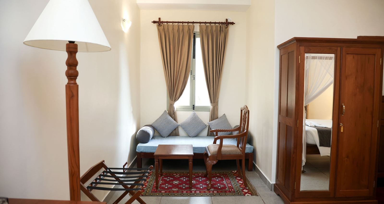 A room that has a sitting area, a cupboard, and a tall lamp | Mango Hill La Serene, Pondicherry