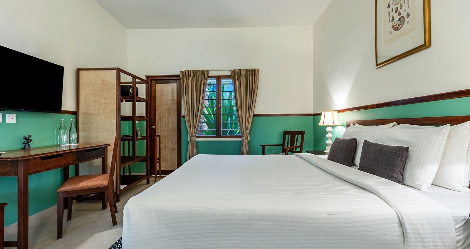 Spacious bedroom featuring a large bed, a desk with a chair, and a television on the wall | Mango Hill Shallow Beach Resort ECR