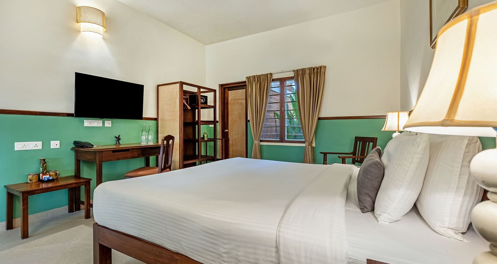 Spacious bedroom featuring a large bed, a work desk, a TV, and a window with curtains | Mango Hill Shallow Beach Resort ECR