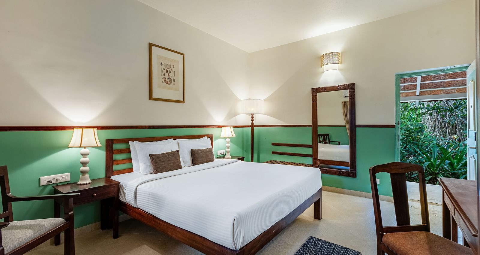 Comfortable bedroom with a wooden bed frame, white linens, bedside lamps, a framed picture, and a window with draped curtains | Mango Hill Shallow Beach Resort ECR