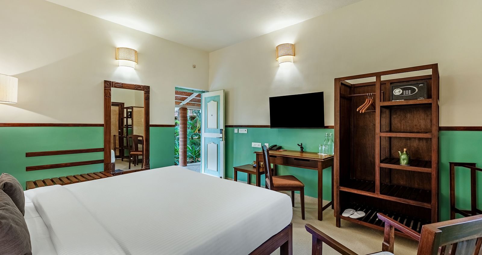 Comfortable bedroom with a king bed, wooden desk and chair, a flat-screen TV, a wardrobe with a safe, and a partially open door | Mango Hill Shallow Beach Resort ECR