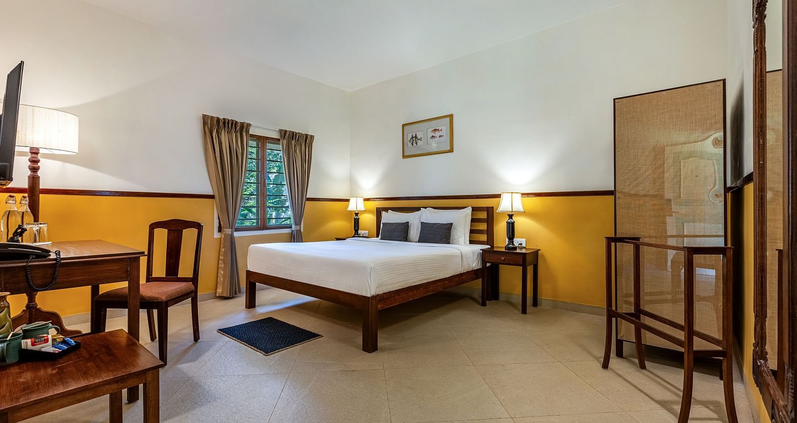 Comfortable bedroom in Pondicherry featuring a double bed, a writing desk, chairs, and a full-length mirror | Mango Hill Shallow Beach Resort ECR