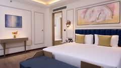 An image of one of the bedrooms in our hotel with a large bed with bed runner and paintings - Sarovar Premiere Amritsar