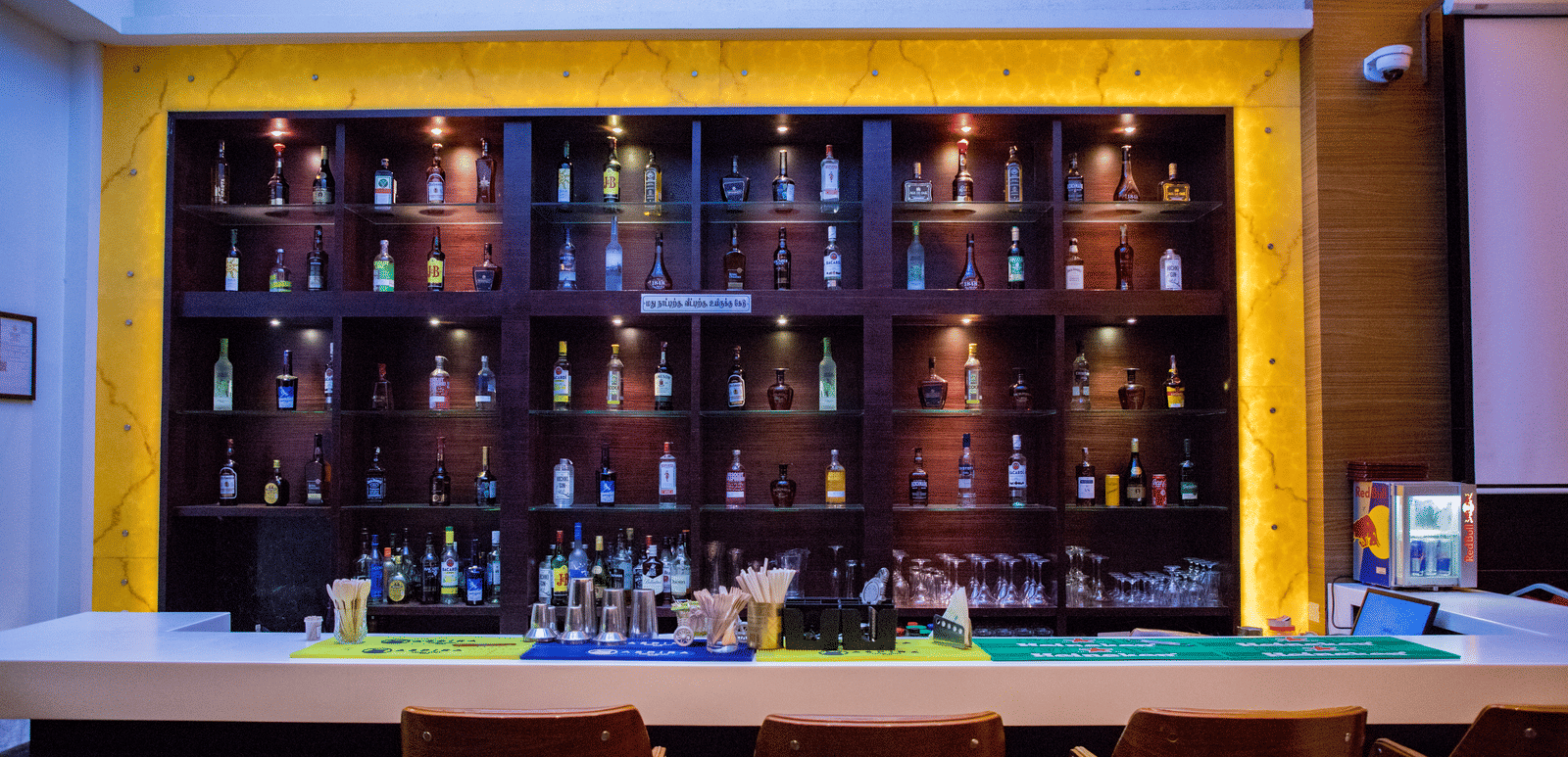 Front view shot of the bar area with an assortment of premium liquor bottles on display behind the bar counter at Benzz Park, Vellore.