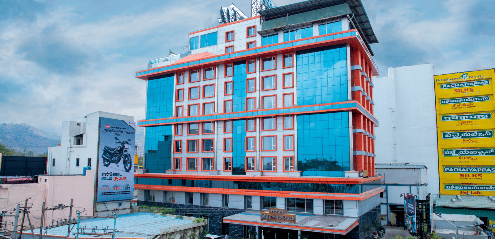 Facade shot of Benzz Park, Vellore, featuring the entrance on the bottom of the building along with a cloudy sky in the background.