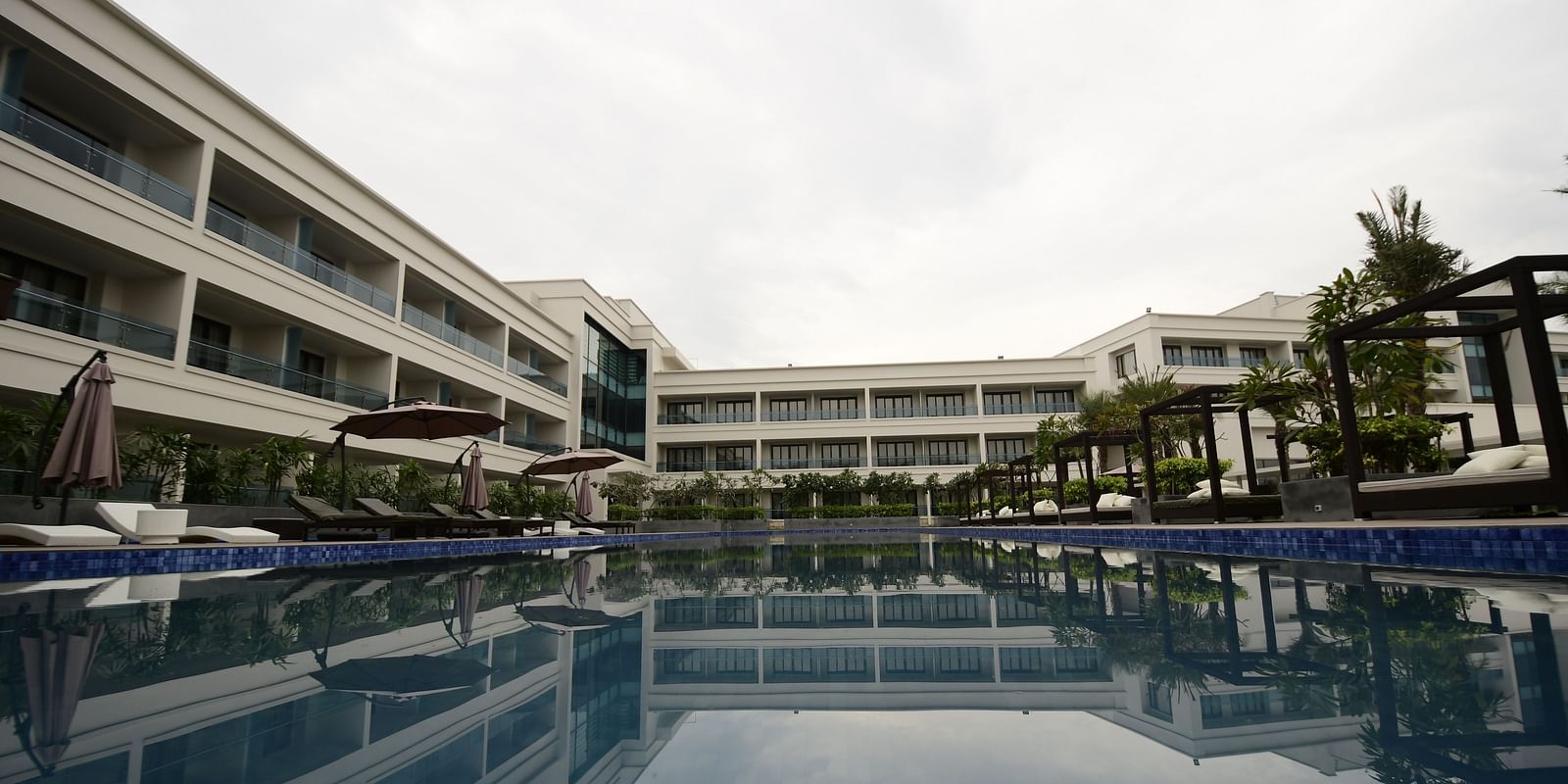 A facade view of the hotel, with the reflection of the building in the swimming pool
