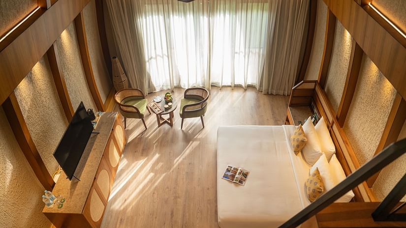 A stunning kind size bedroom with high ceilings, seating area, and large windows allowing natural light at Ananta Spa and Resort, Ajabgarh.