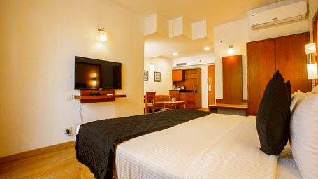 Premier Room with a large bed, wall mounted television and wooden furnishings at Featherlite Evoma Hotel.