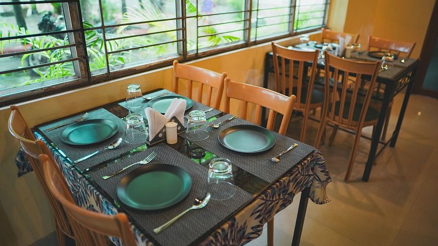 Two sets of dining tables, each with four chairs, are arranged near a window, allowing natural light to fill the space