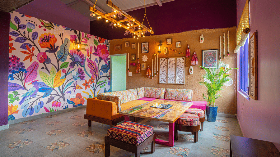 A room with a 2 sofas, wall paintings, chairs, and decor items arranged indoors at Adrushya Estates, Mukteshwar.