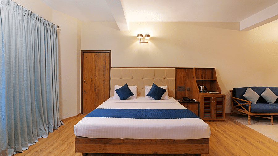 An image of a room with spacious layout, a queen size bed, a couch, and soft lighting - Cross Roads Inn, Bengaluru