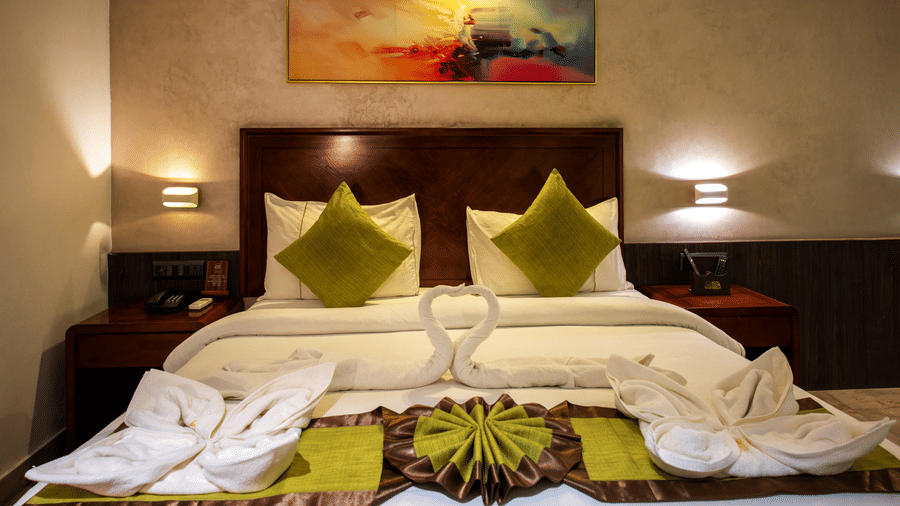 Superior Room with double bed, yellow-green cushions, and wall art at Hotel Sonar Bangla, Taki.