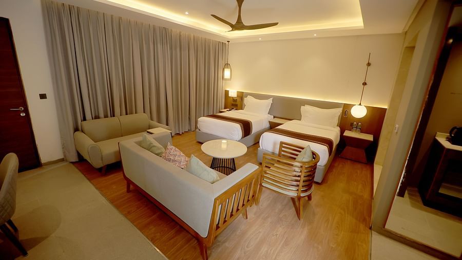Spacious room with twin seating area, centre table, and ambient cove lighting above the bed at Wyndham Garden.