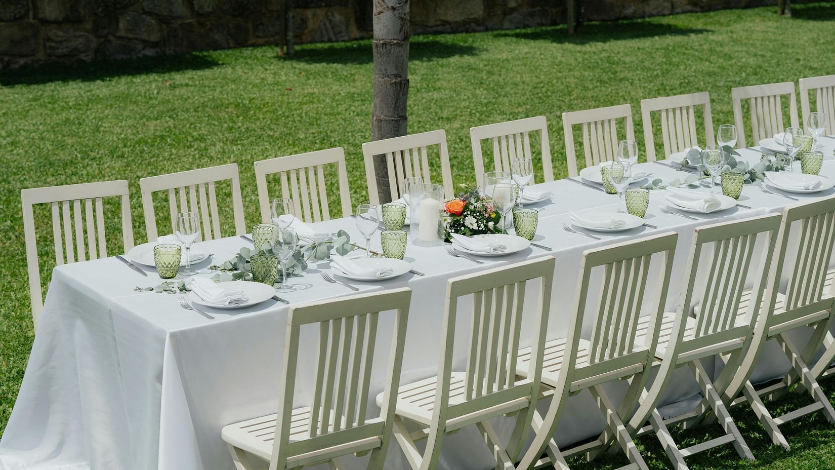 An image of a lawn where chairs and tables are lined up in order with cutlery and floral decoration