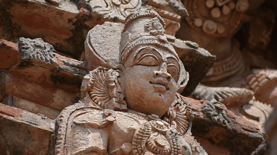  Detailed ancient stone carving of a deity from a Dravidian-style temple.
