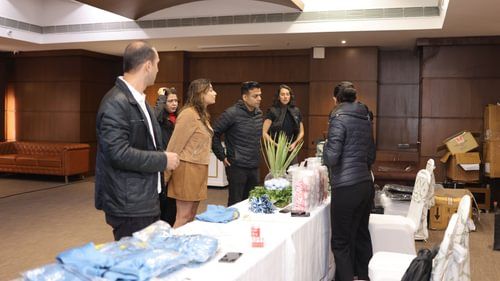 A group of people gathered in the exhibition room where several items are placed on a table for annual gold celebration at Heritage Village Resorts & Spa